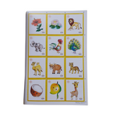 A page displaying twelve individual cards or illustrations, likely for teaching Sanskrit vocabulary. Each card features a colorful drawing of a plant or animal (hibiscus, lotus, lion, elephant, rooster, peacock, camel, bull, leopard, coconut, mango, giraffe) along with text in Devanagari script identifying each item.